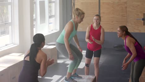 Unaltered-diverse-women-motivating-determined-woman-jumping-on-boxes-at-fitness-class,-slow-motion