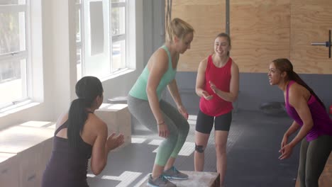 mujeres diversas inalteradas motivando mujeres determinadas saltando en cajas en clase de gimnasia, cámara lenta