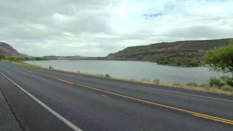 pov del pasajero de una clase a rv estacionada, punto de vista del lago azul y tráfico en la autopista 17 en el estado de washington en un día nublado y ventoso