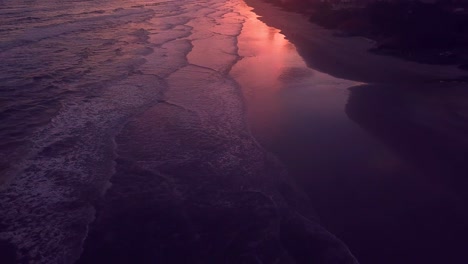 flying over waves in brazilian beach on atlantic ocean in sunset, beautiful pink skies aerial shot