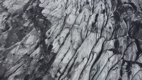 aerial view around dirty, blackened glacier surface, in iceland - orbit, drone shot