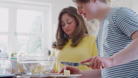 Junges-Down-Syndrom-Paar-Fügt-Butter-Zum-Kuchenrezept-Hinzu,-Das-Sie-Zu-Hause-In-Der-Küche-Backen