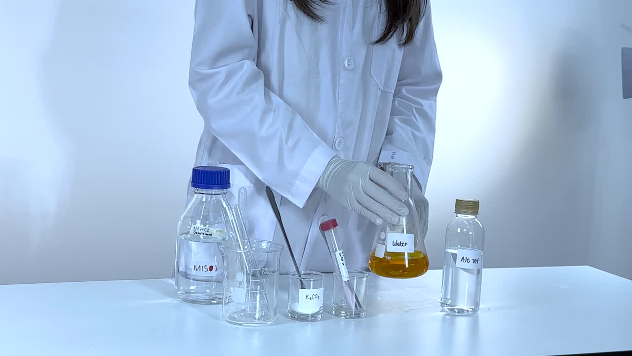Scientist conducts a chemistry experiment with potassium carbonate, showcasing color changes in a controlled laboratory environment