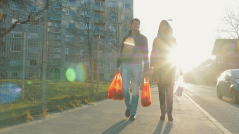 una pareja con bolsas yendo a casa después de las compras.