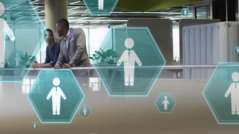 animation of profile icons floating over diverse businessman and businesswoman discussing at office