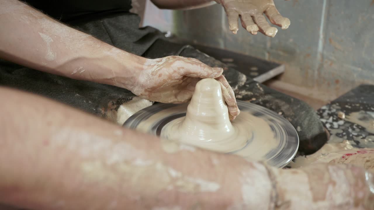 un alfarero enseña a una mujer a hacer platos de arcilla. un hombre toma las manos de una mujer