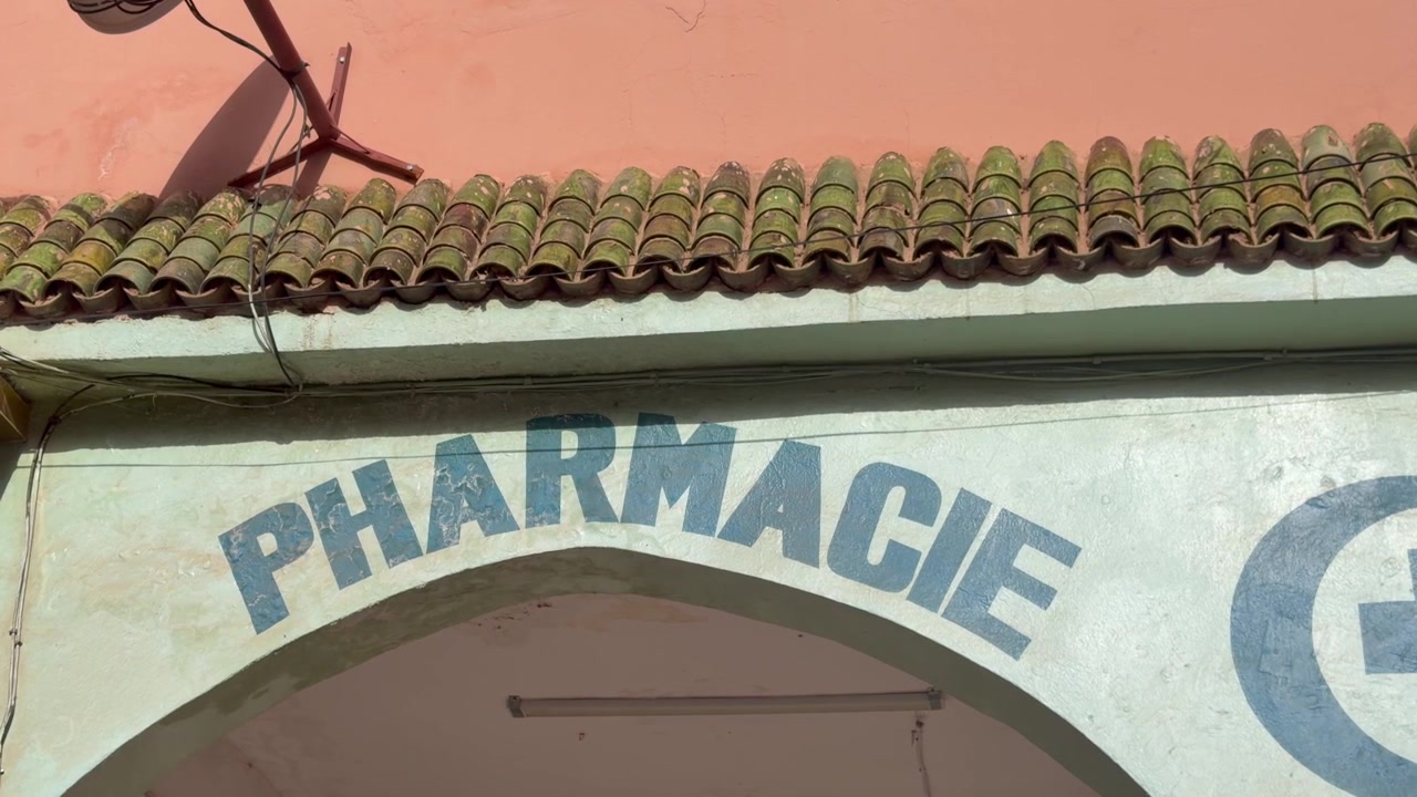 Insegna della farmacia su parete esterna con arco curvo e tegole del tetto