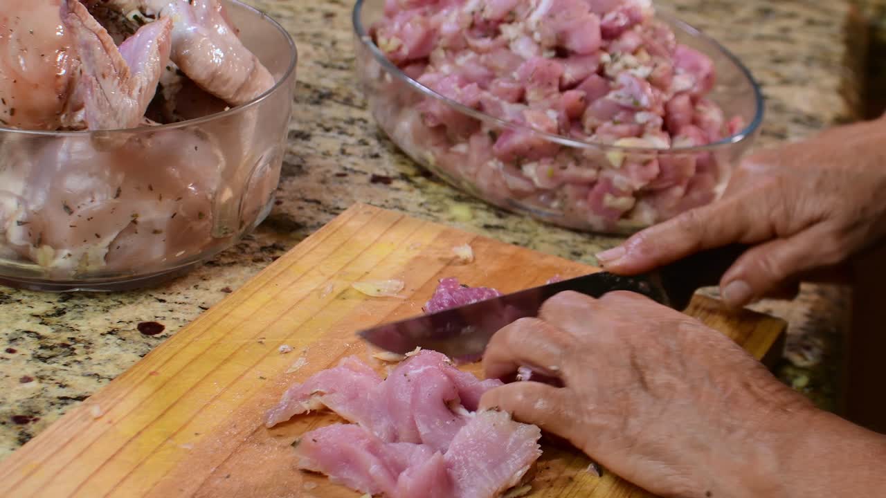 Authentic, slow food preparation: close-up, intimate view of aged hands diligently chopping fresh, marinated poultry and pork for a home-cooked recipe