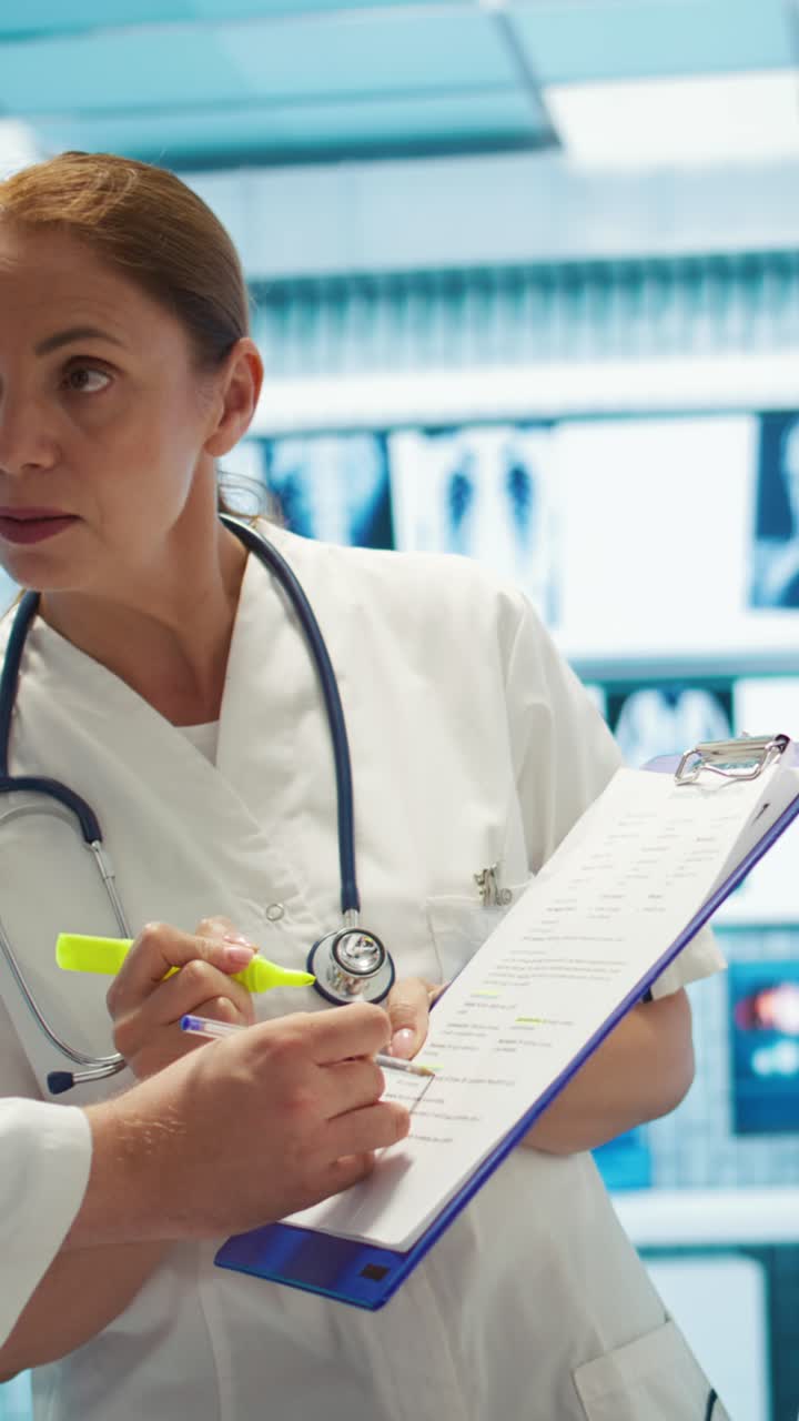 Video Vertical: Equipo de expertos médicos resaltando resultados de radiografías en historiales médicos