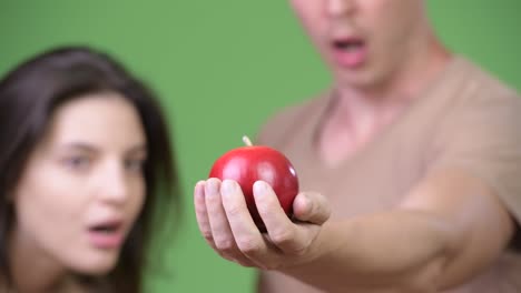 young couple looking surprised at apple together