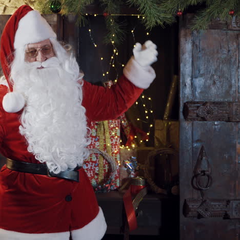 santa claus in red and white costume gesturing a lot. santa with white beard is waving his hands on the background of christmas presents. christmas atmosphere inside the house.