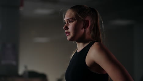 young motivated and tired sportswoman in training hall in evening female athlete is breathing hard