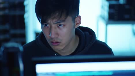 a focused individual engaged in computer work, deep in thought and concentration, surrounded by an array of technology and ambient light