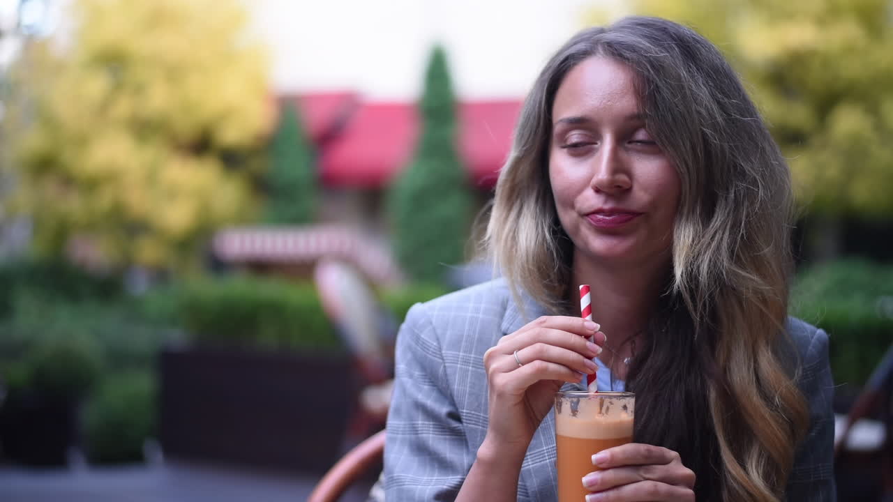 Close up of a woman drinking an orange and carrot juice at a terrace