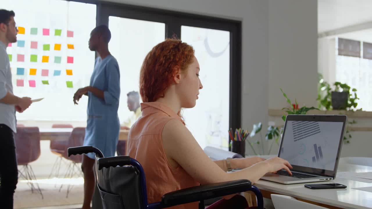 Vista laterale di una giovane donna d'affari caucasica con disabilità che lavora al laptop in un ufficio moderno 4k