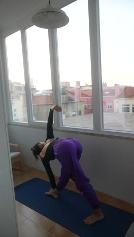 woman practicing triangle pose yoga on balcony