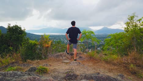 Man-enjoying-the-view-over-the-sleepy-city-of-cairns-in-the-morning,-clouds-in-the-sky-and-covering-the-mountains,-slow-motion