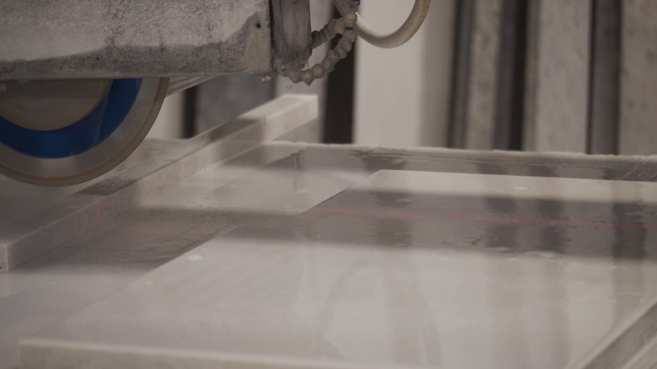 Slow motion cabinet maker cutting granite worktop with industrial water cooled table saw.