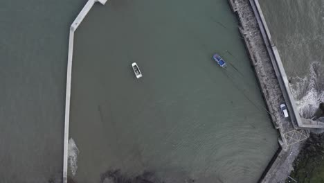 rising coastal aerial reveals boats protected by concrete breakwater