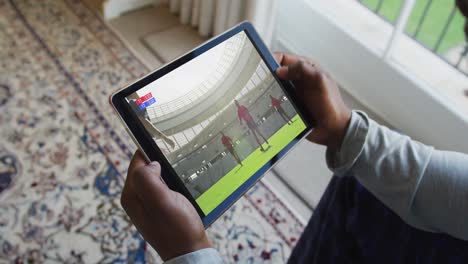 Zusammensetzung-Eines-Mannes,-Der-Zu-Hause-Sitzt-Und-Sich-Ein-Rugbyspiel-Auf-Einem-Tablet-Anschaut