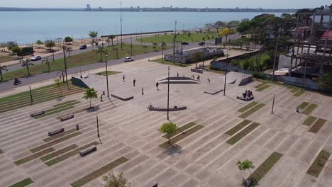 drone wide pull-away from kids at skate park with blue ocean in the background