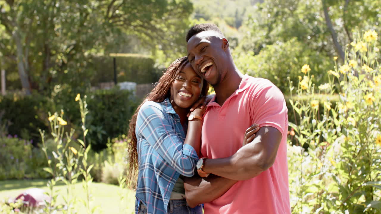 Smiling African American couple embracing outdoors, enjoying time together in sunny garden