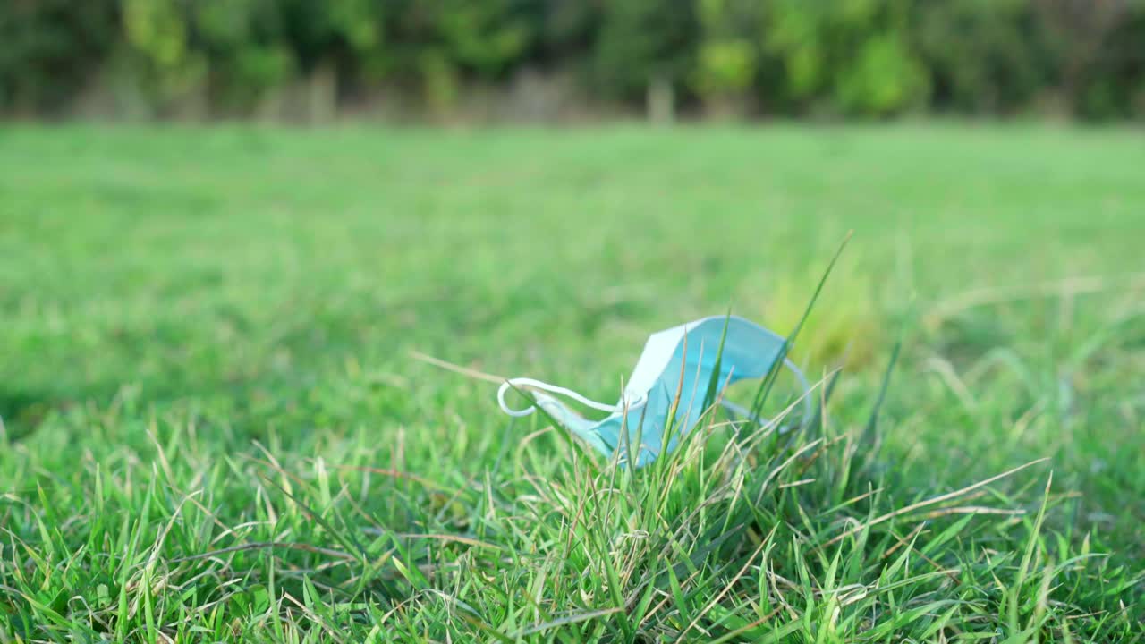 코로나 바이러스 covid-19 전염병 동안 푸른 잔디에 버려진 의료 보호 얼굴 마스크, 자연 오염