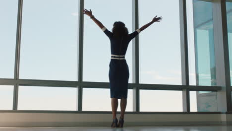 happy busienss woman celebrating success with arms raised looking out window feeling successful in office confident female enjoying achievement