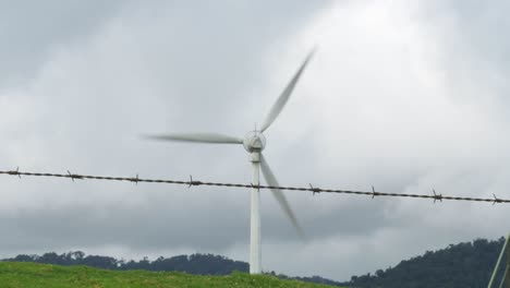 Windkraftanlage-An-Hügeltalgrenze-Mit-Stacheldraht,-Verkleinerte-Aufnahme