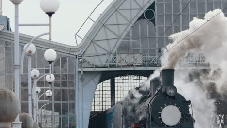 tren de locomotora de vapor que se acerca a la estación pasando por el patio de mercancías