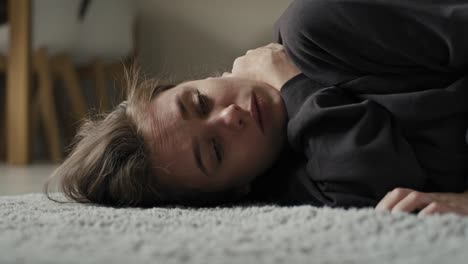 caucasian woman lying down at the carpet in home with mental problem.