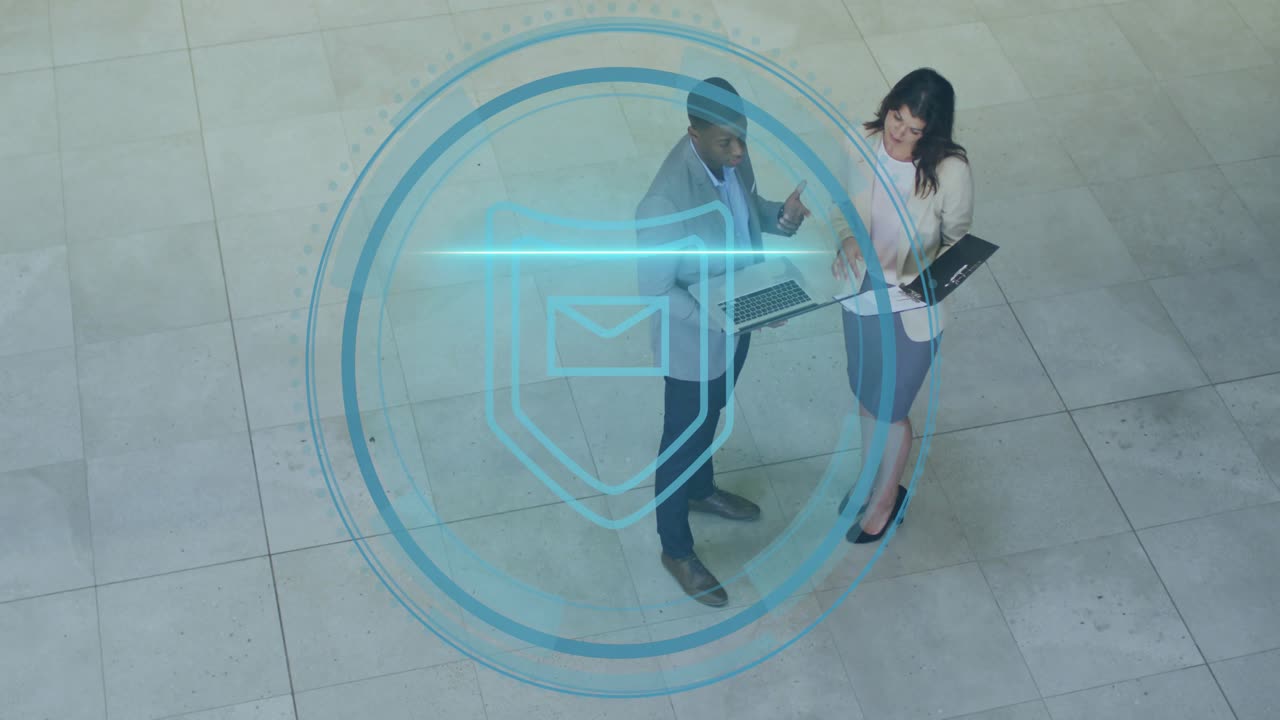 Colleagues pointing at laptop discussing cyber security as rings forming into shield envelope icon