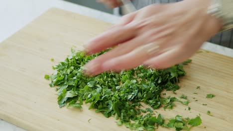 Woman-cutting-parsley-on-wooden-board