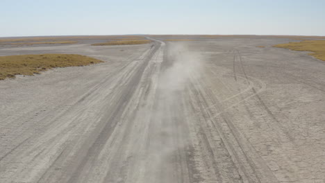 Front-View-Of-4x4-Car-Driving-On-A-Dusty-Makgadikgadi-Salt-Pan-On-A-Sunny-Summer-Day-In-Botswana