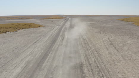 front view of 4x4 car driving on a dusty makgadikgadi salt pan on a sunny summer day in botswana