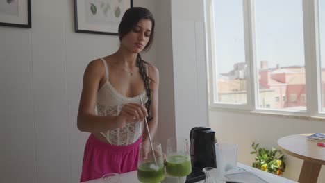 woman making green smoothie in kitchen