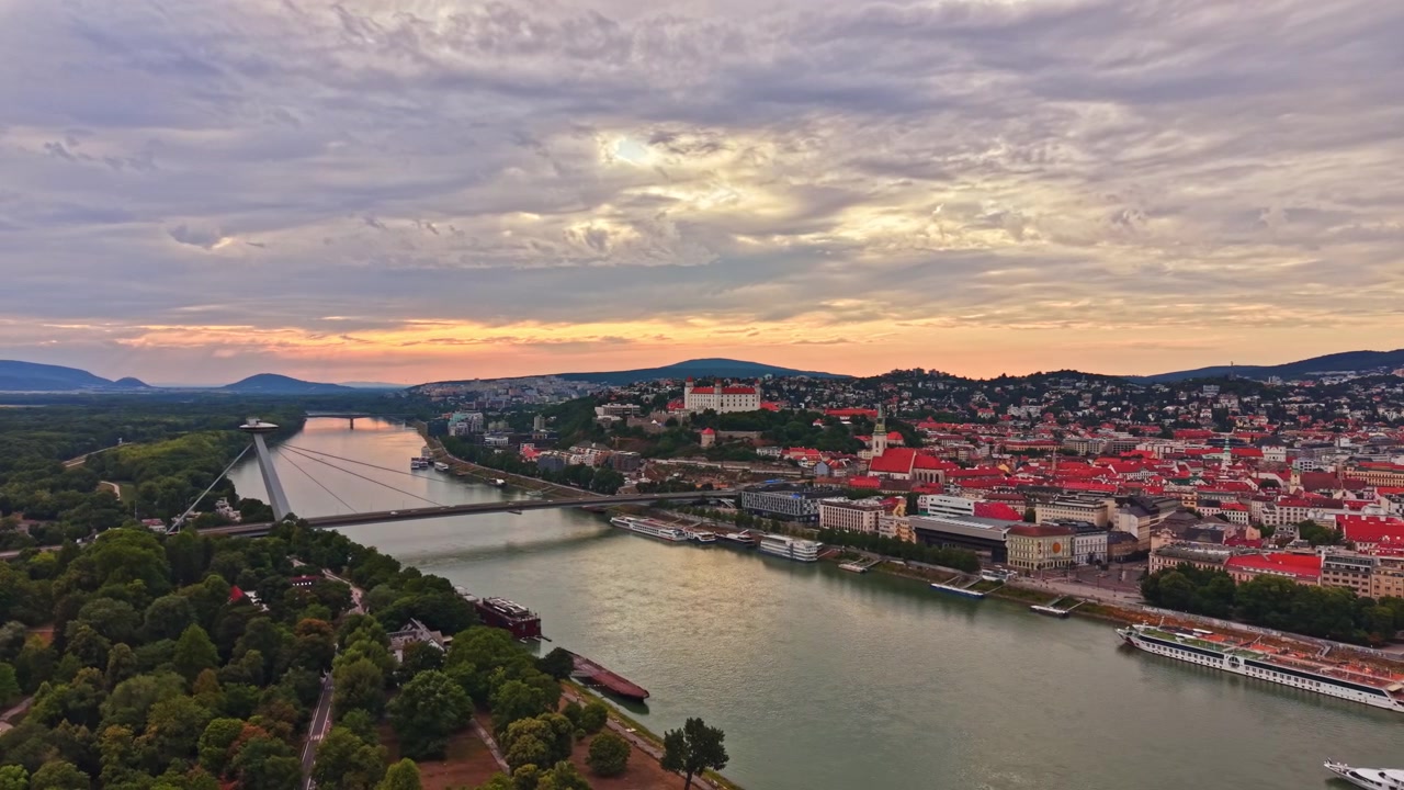 Vue du coucher de soleil sur le Danube avec des bâtiments et des collines en arrière-plan