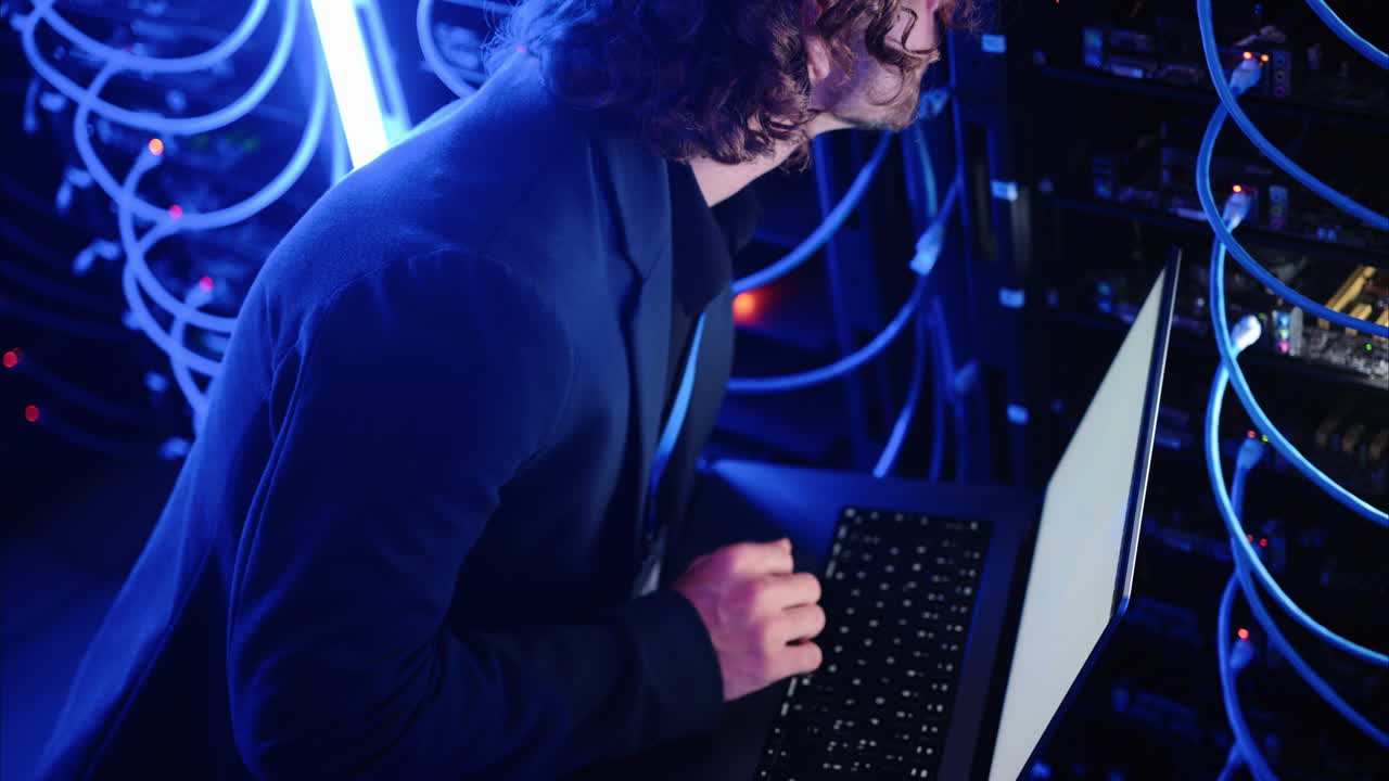 Man analysing servers and programming on a computer in a data center