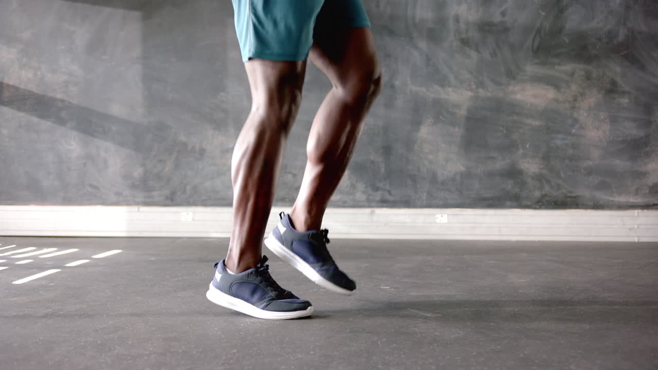 Exercising in gym, african american man in athletic shorts and sneakers, focus on legs, copy space