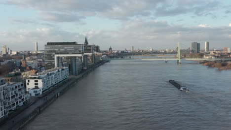 Vorwärts-Fliegen-über-Den-Breiten-Rhein-In-Der-Stadt.-Frachtschiff,-Das-Kranhäuser-Umfährt.-Köln,-Deutschland