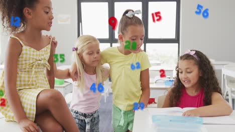 Animation-of-numbers-over-happy-diverse-schoolgirls-talking-in-classroom