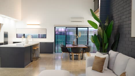 modern kitchen and dining room with large dining table island bench top, polished concrete flooring and high ceiling luxury home house