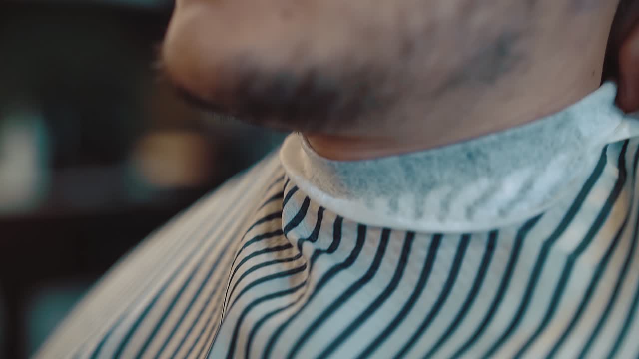 Berberde sakalını ve saç stilini yaptırmak için hazırlanan genç yakışıklı adam, yakın çekim ağır çekim