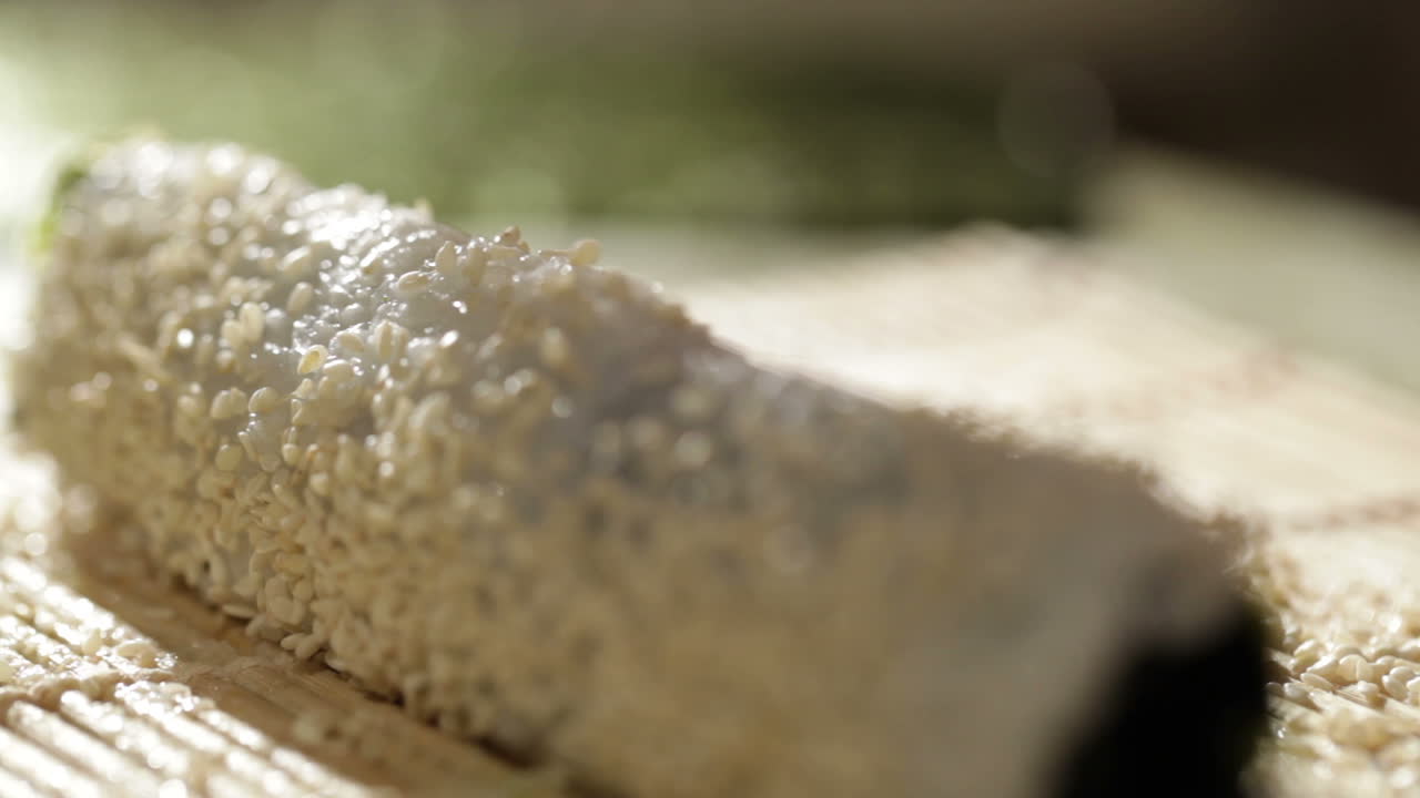 poniendo sésamo en el rollo de sushi