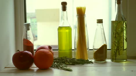 Food-ingredients-near-kitchen-window.-Cooking-oil-and-kitchen-herbs