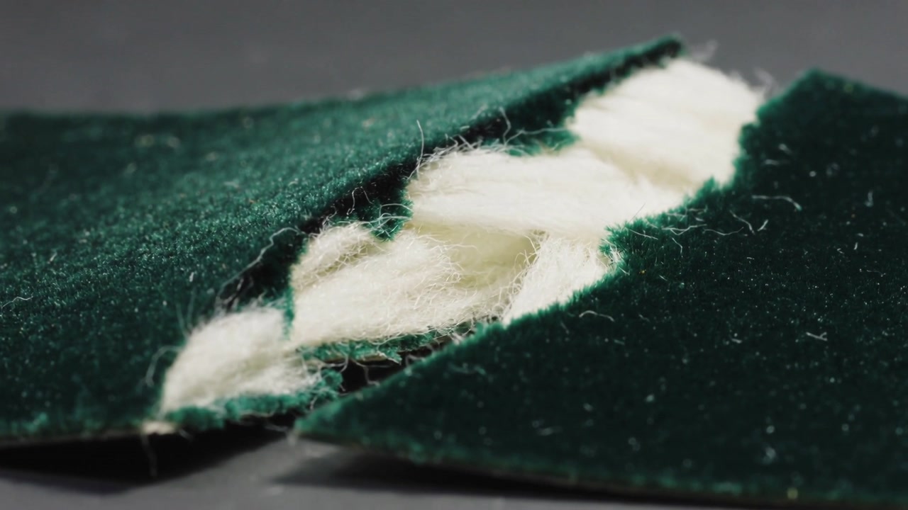 Frames showing torn green velvet panel lifting revealing white fill and dark backing on gray bench