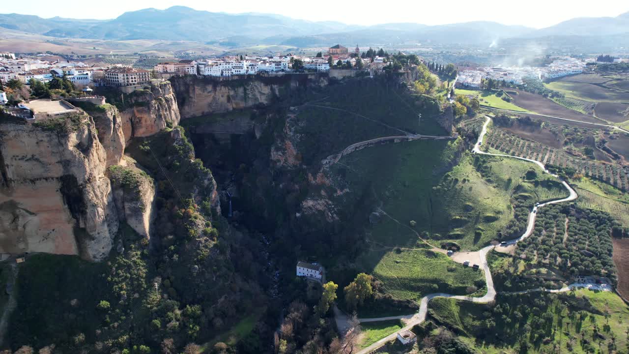 스페인 의 고급 주택 들 은 론다 절벽 에 자리 잡고 있으며, 그 아래 에는 농업 과 농장 들 이 있다
