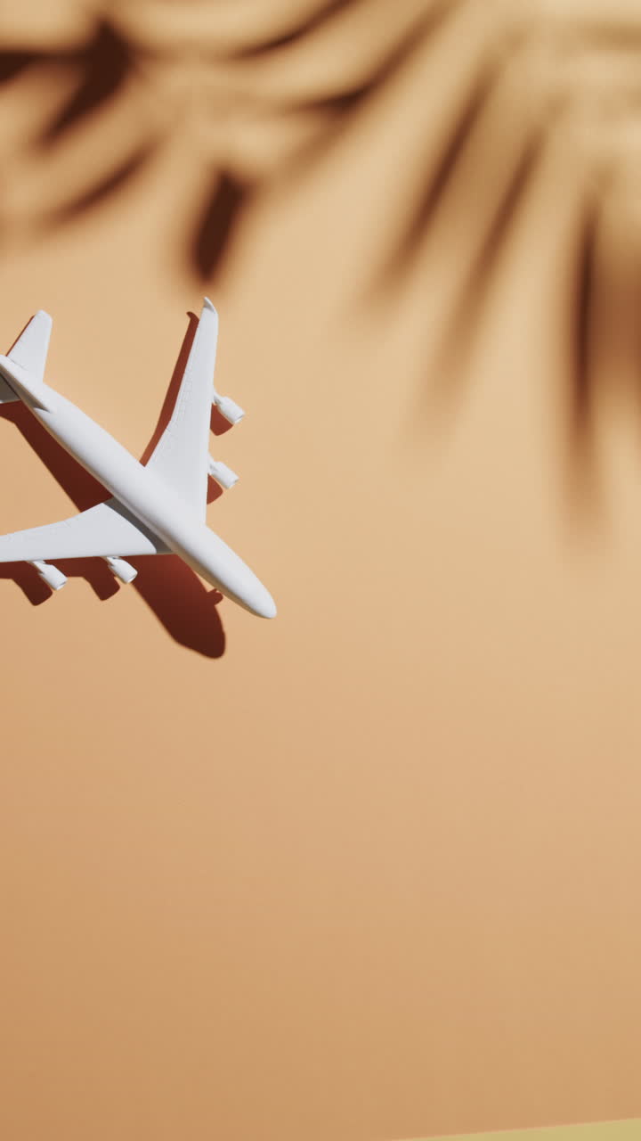 Vertical video of white airplane model with leaf shadow and copy space on orange background