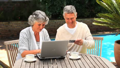 retired couple using a credit card to buy online