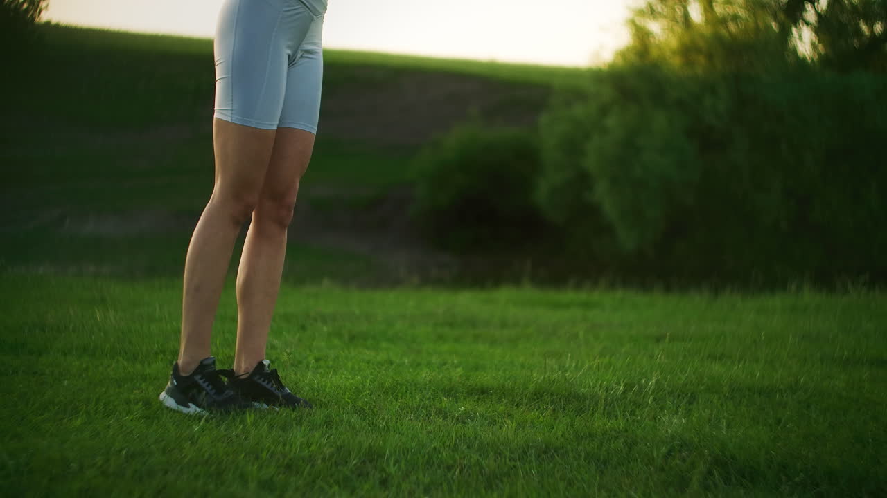 The camera follows a female athlete lunging in pairs at sunset. Move by squatting on each leg in turn. Close up training in the Park in the summer